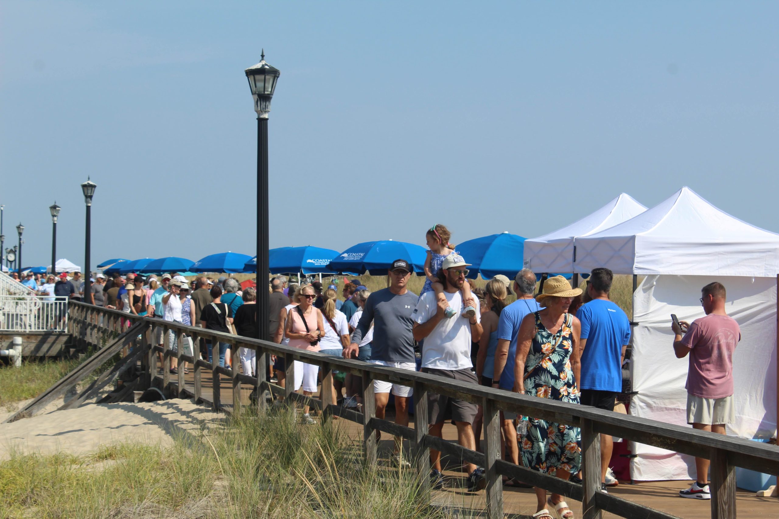 People walking around looking at art pieces at the Bethany Beach Boardwalk Arts Festival